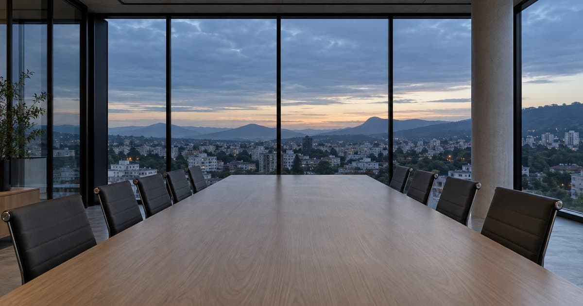 Sala de reunião moderna e vazia, com parede de vidro e a cidade ao fim da tarde, cenário de uma landing page para advogados